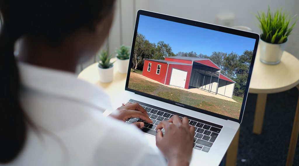 woman looks at red metal barn on laptop